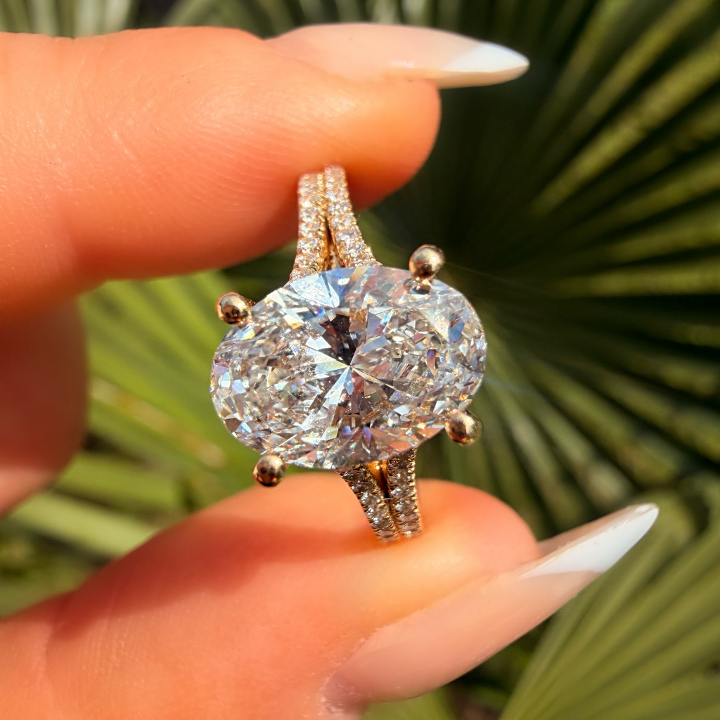 Diamond ring held between fingers with a green leafy background
