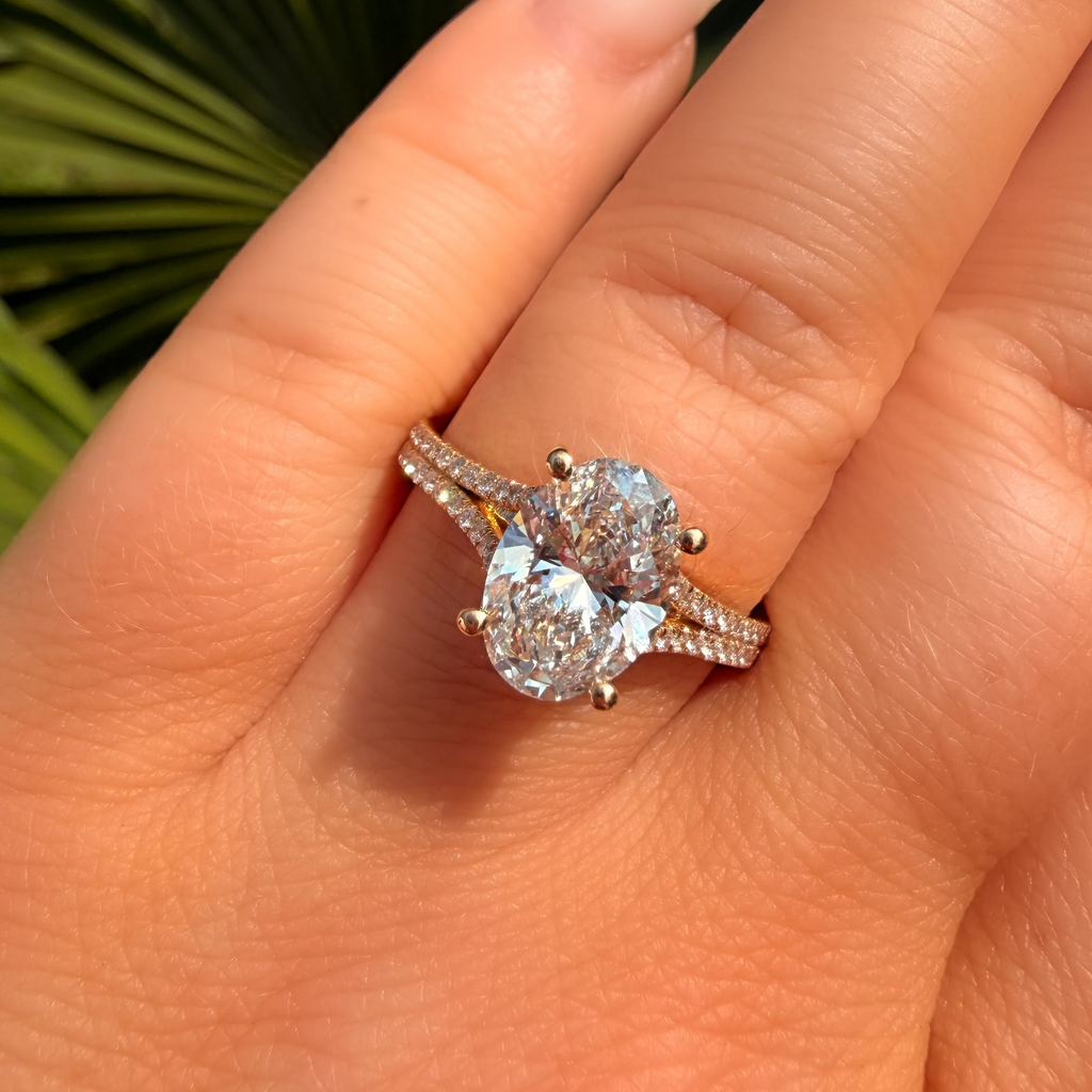 Close-up of a hand wearing a diamond ring with a blurred green leaf background