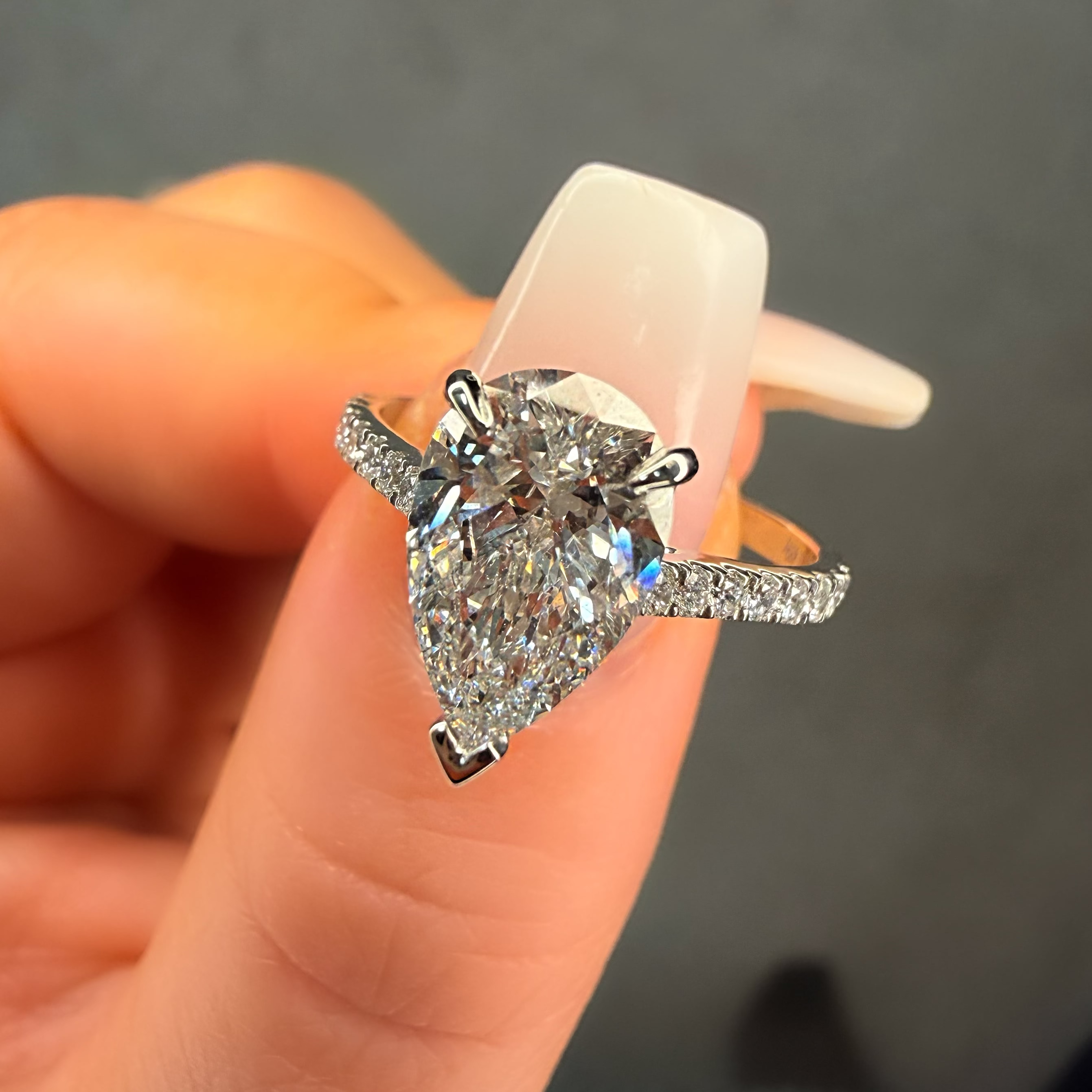 Diamond ring held between fingers against a neutral background