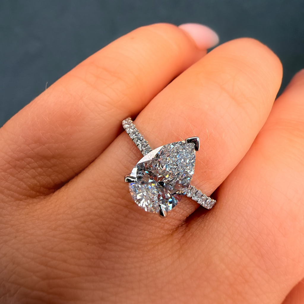 Diamond ring on a finger against a dark background