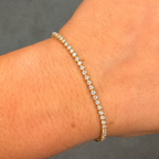 Gold bracelet with diamonds on a wrist against a gray background