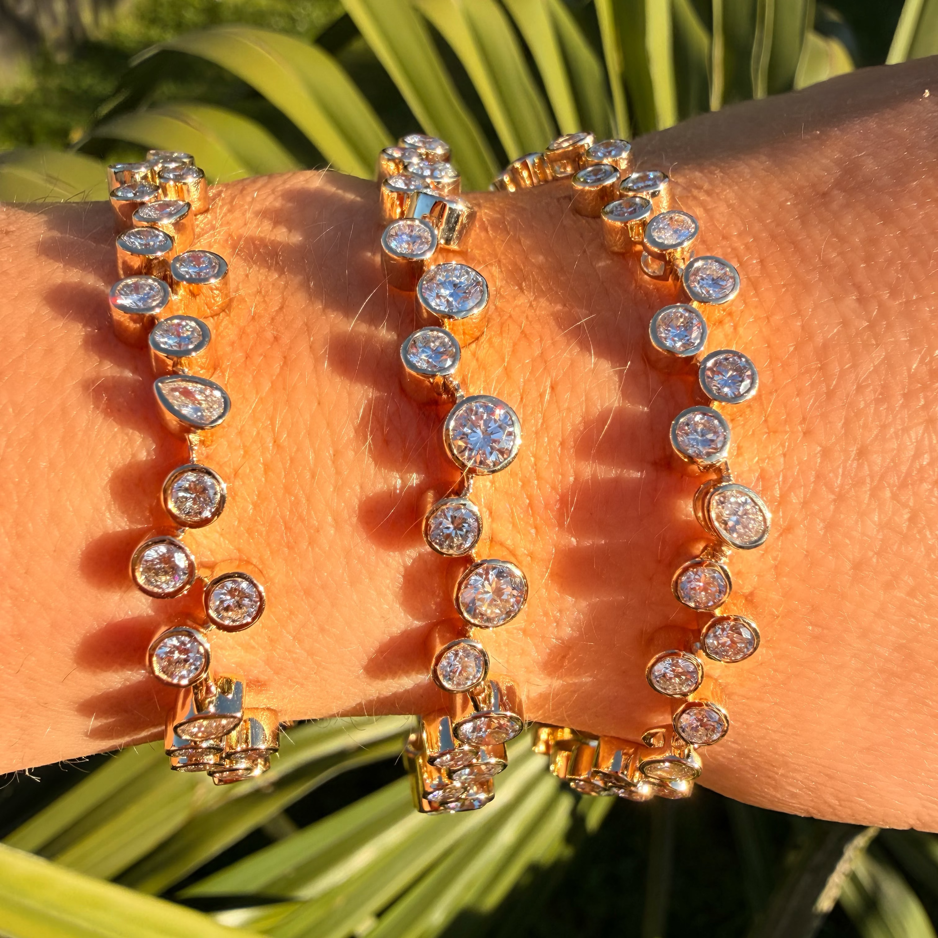 Gold bracelet with clear stones on a wrist against a green leafy background
