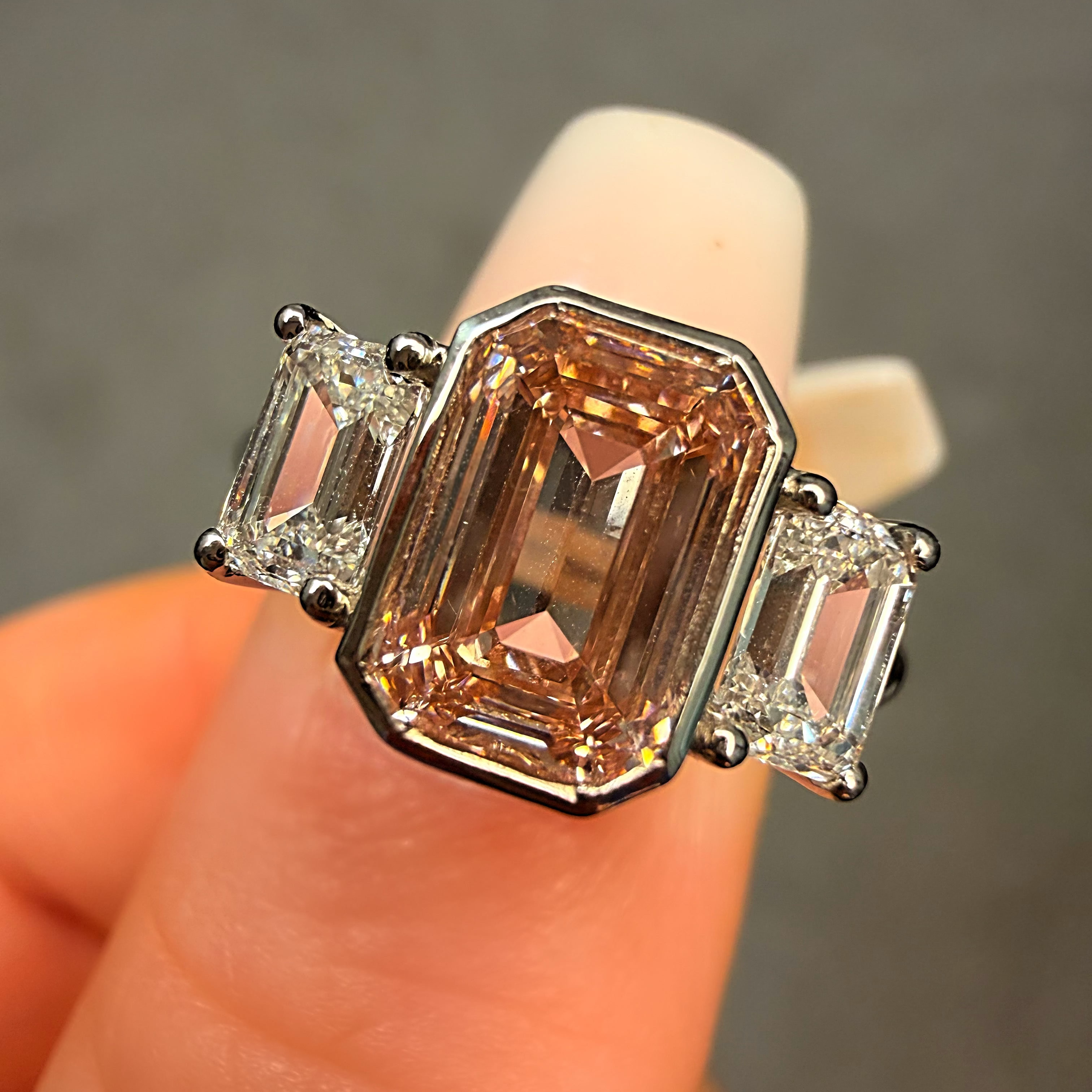 Ring with a large brown gemstone and smaller clear stones on a finger against a neutral background