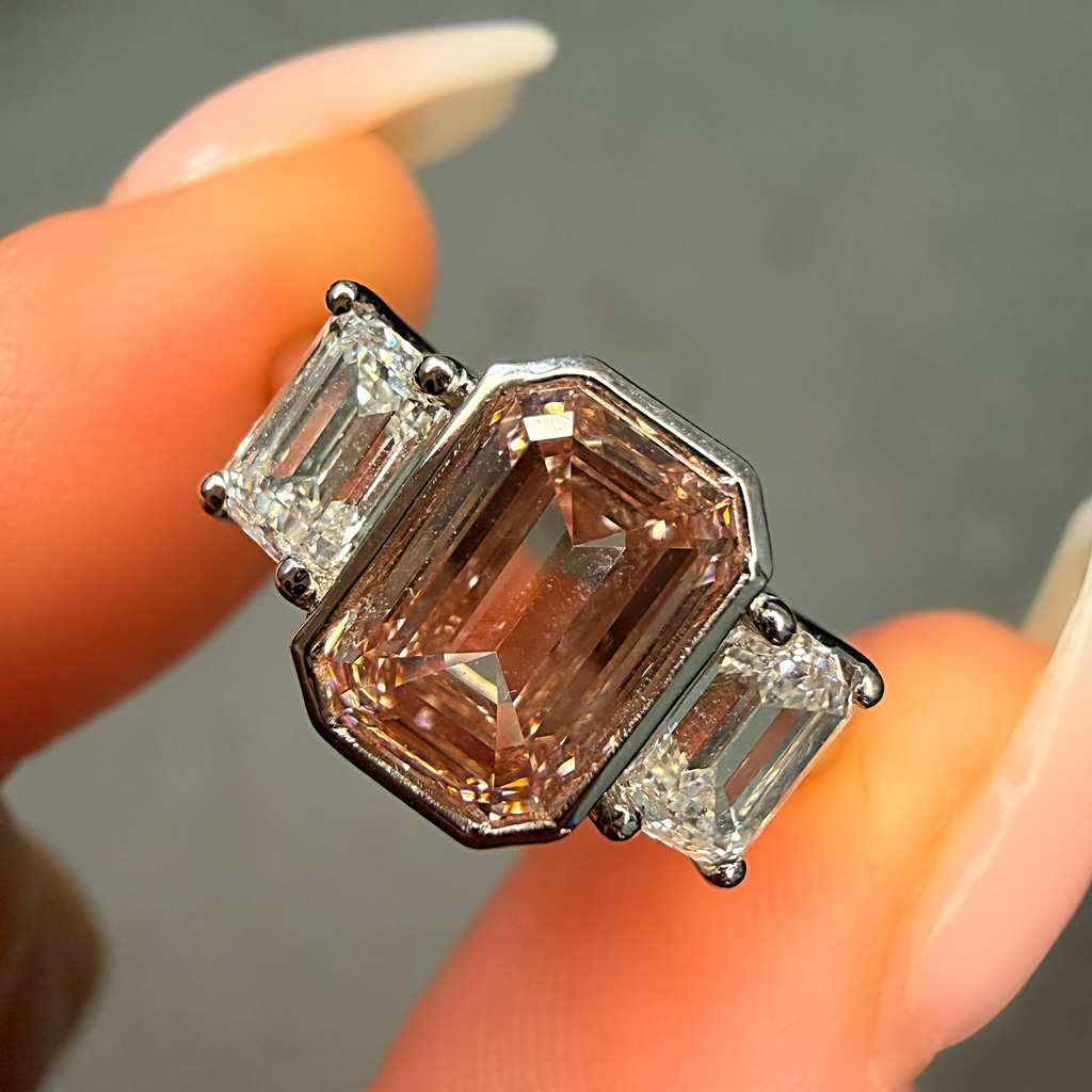 Diamond ring with a pink center stone held between fingers against a neutral background