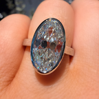 An oval-cut iridescent gemstone ring set in a rose gold band, worn on a person's finger.