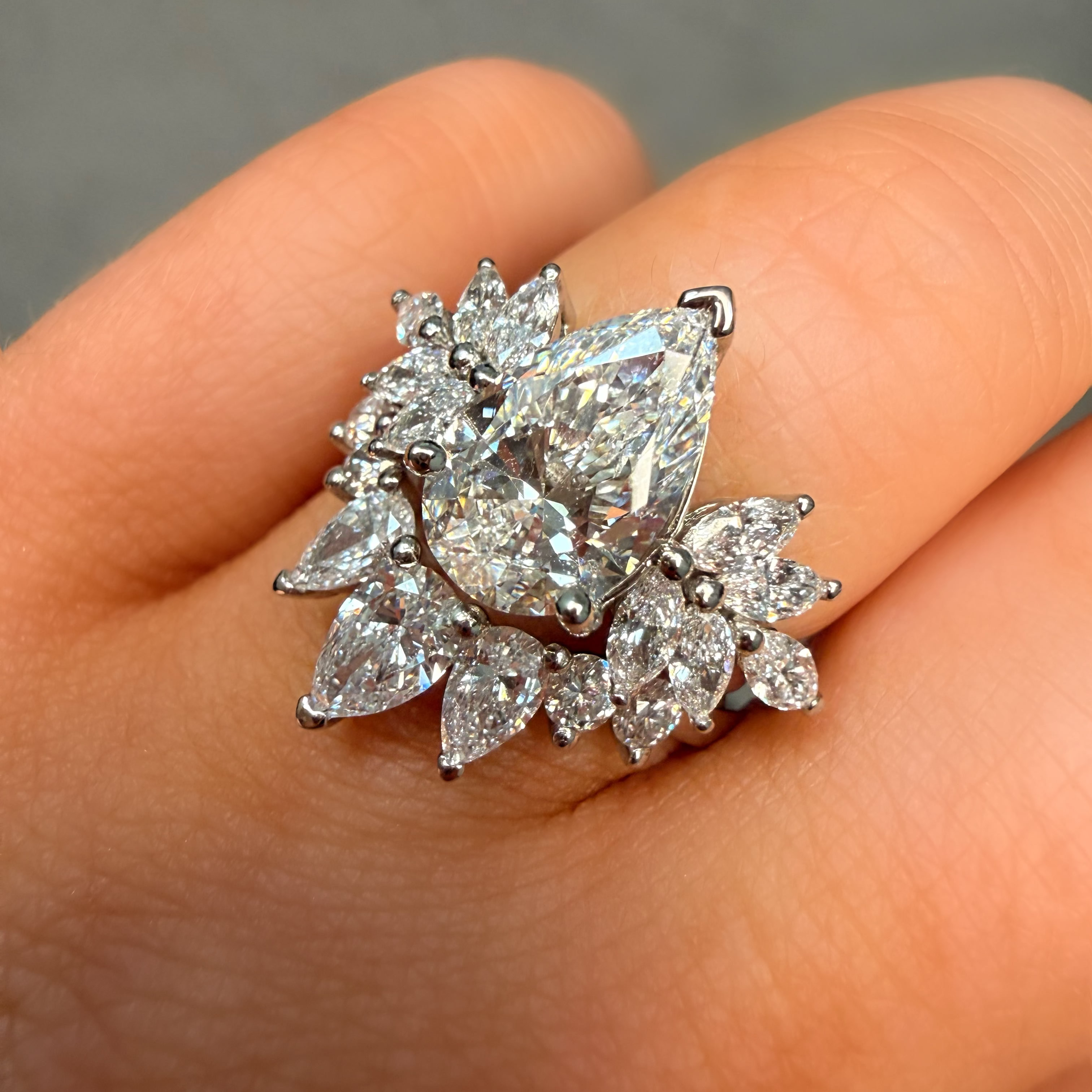Diamond ring held on a hand against a neutral background