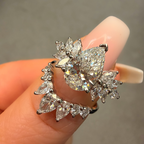 Diamond leaf-shaped earring held between fingers against a neutral background
