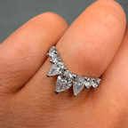 Silver diamond earring on a finger against a neutral background