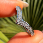 Silver ring with diamonds on a finger against a blurred natural background