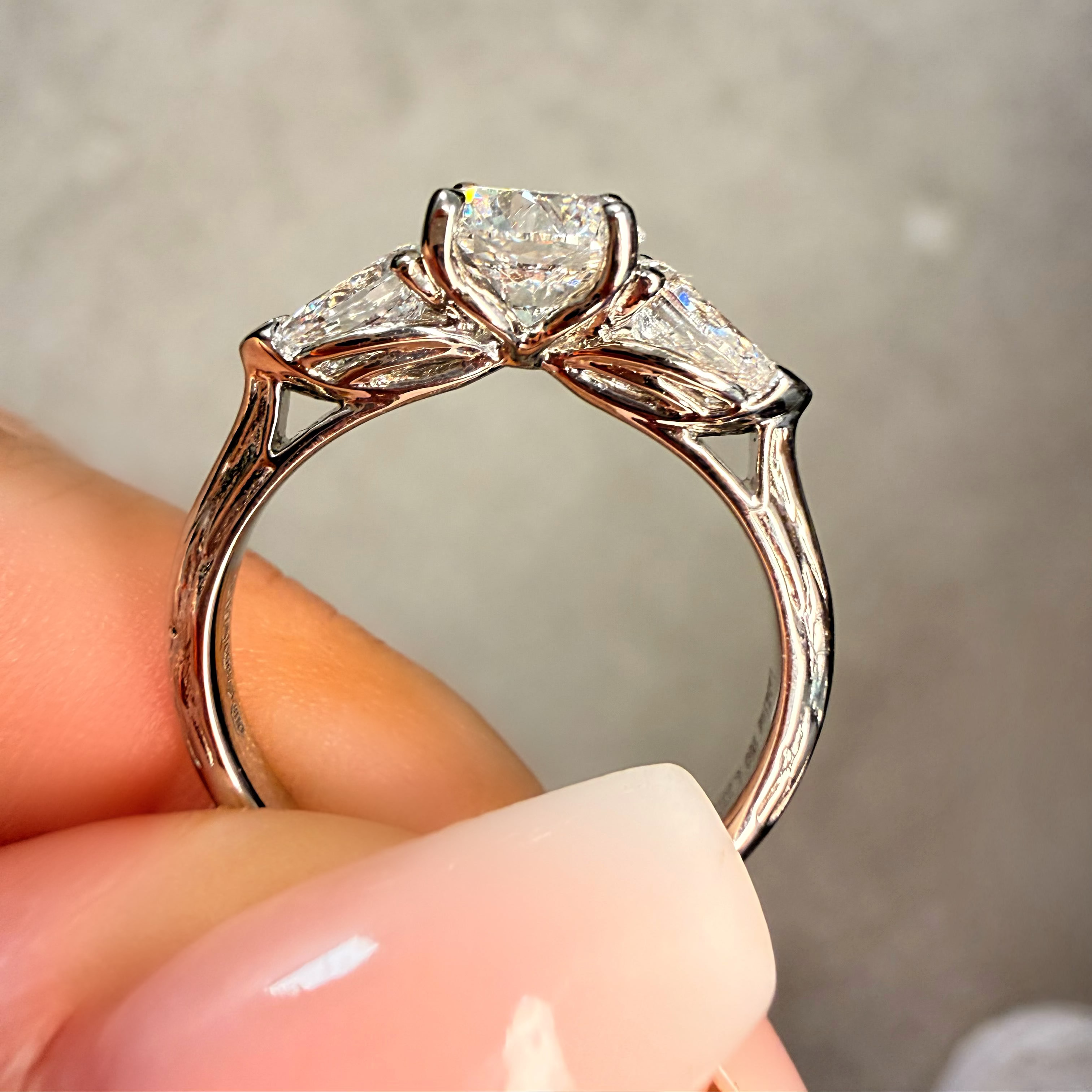 Rose gold ring with a heart-shaped diamond held by a hand against a neutral background