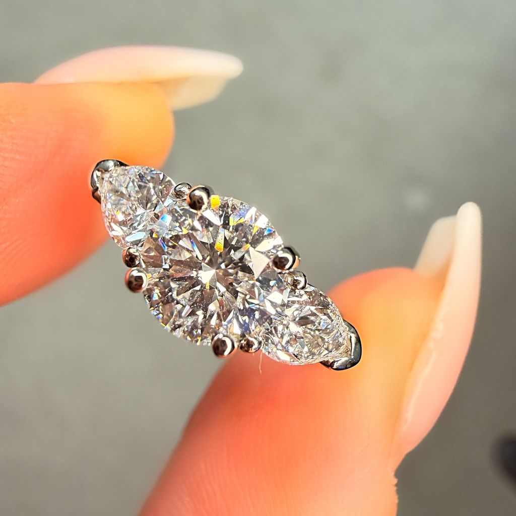 Diamond ring held between fingers with a blurred background