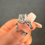 Silver ring with a large diamond held in a hand against a dark background