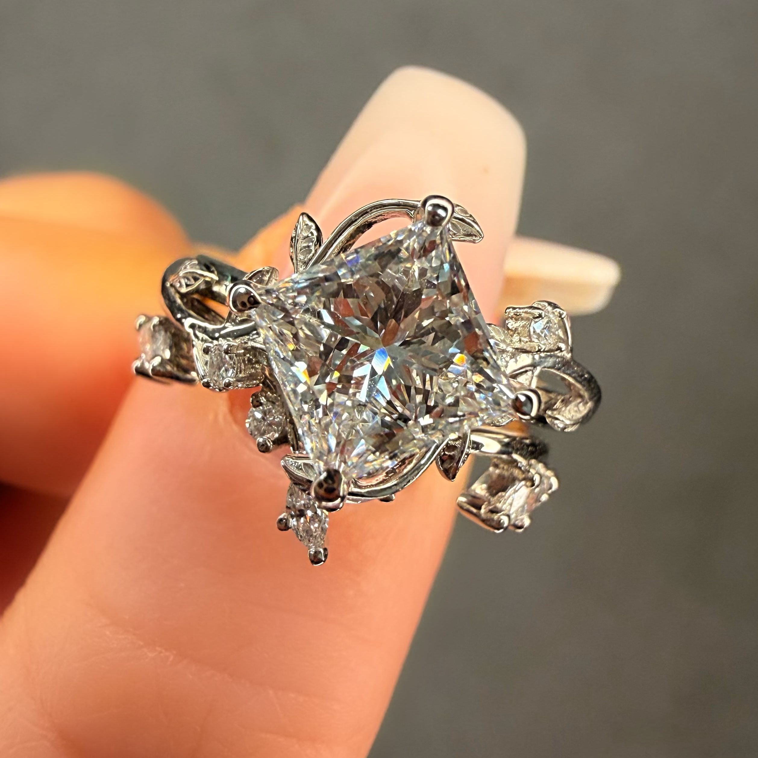 Diamond ring held on a finger against a neutral background