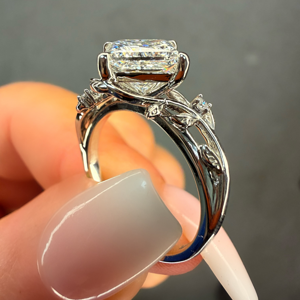 Silver ring with a large diamond held by a hand against a dark background
