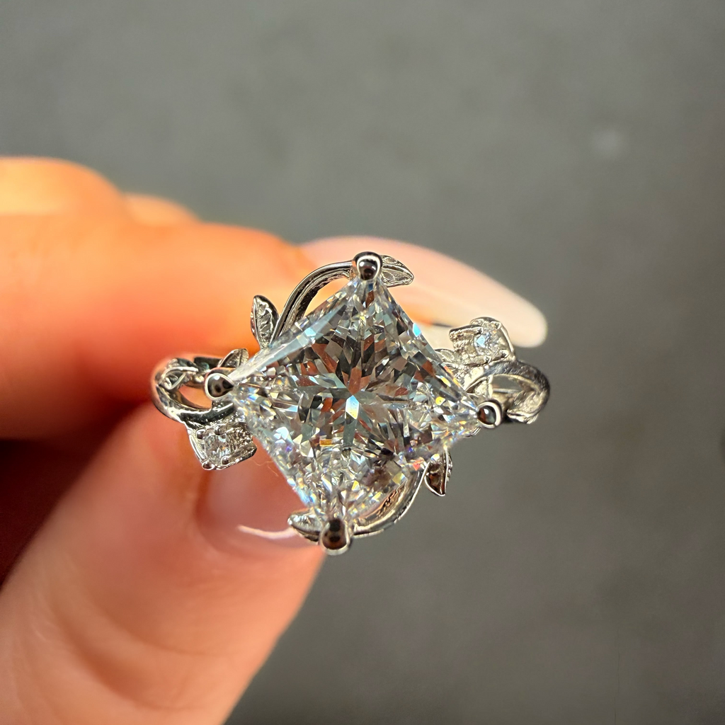 Diamond ring held between fingers against a neutral background