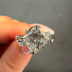 Diamond ring held between fingers against a neutral background
