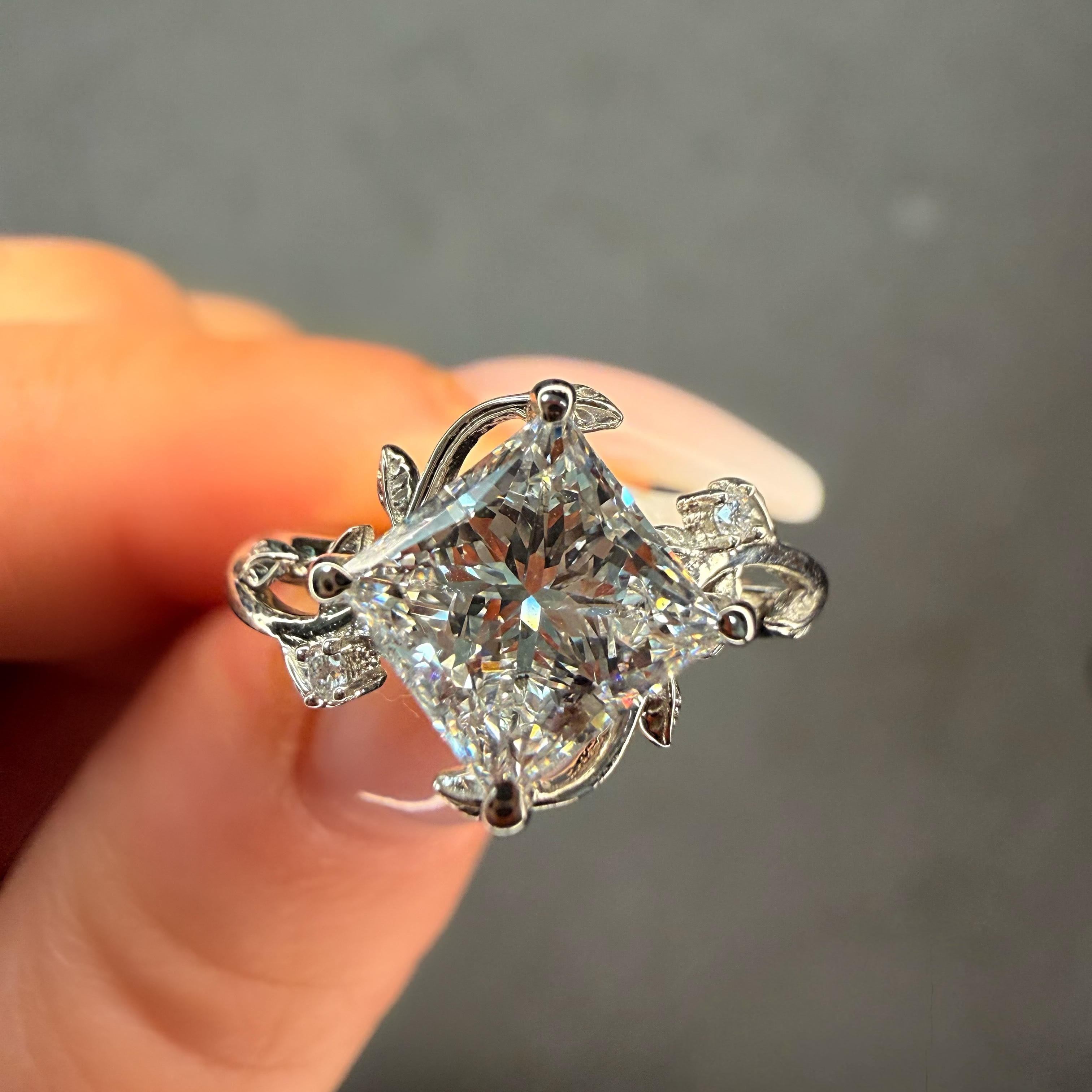 Diamond ring held between fingers against a neutral background