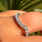 Silver ring with diamonds on a person's finger against a blurred green background