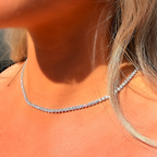 Close-up of a person wearing a silver necklace with a blurred background