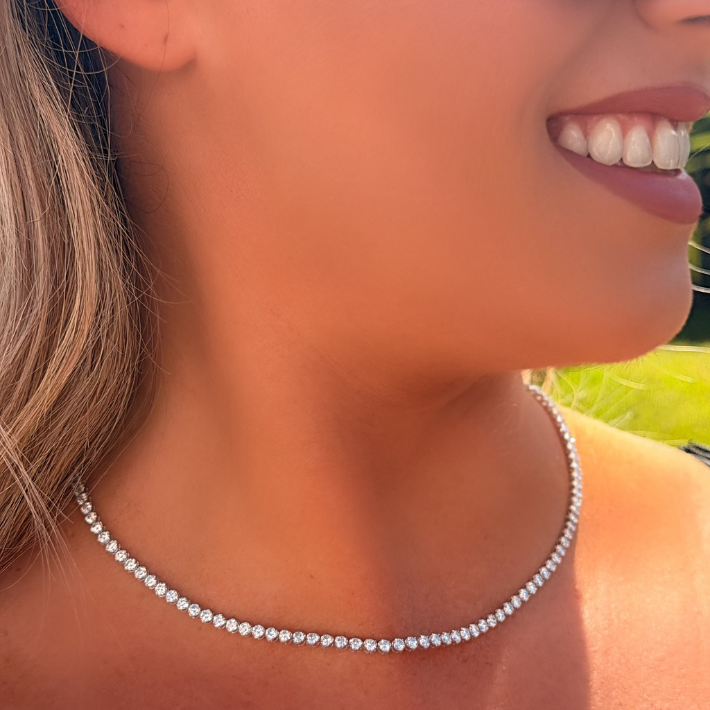 Close-up of a woman wearing a pearl necklace with a blurred outdoor background