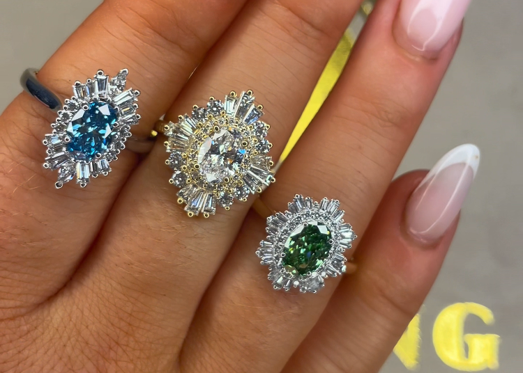 Three diamond rings with different colored gemstones on a hand.