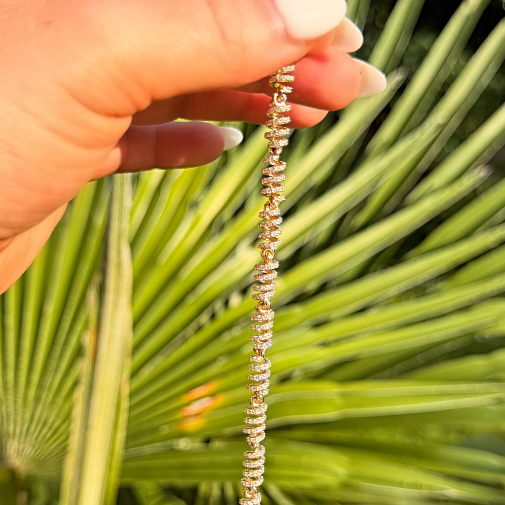 Hand holding a beaded necklace against a green leafy background