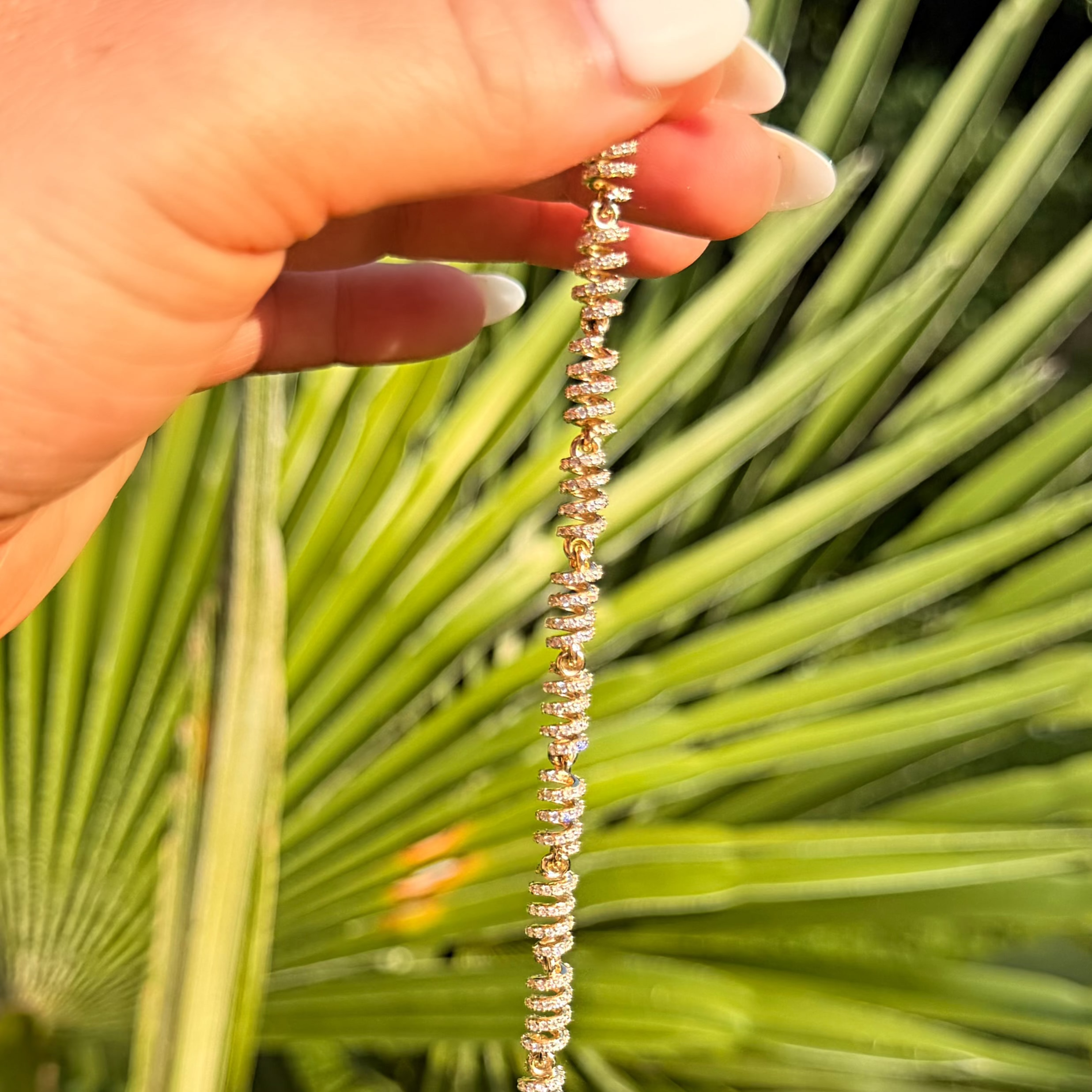 Hand holding a beaded necklace against a green leafy background