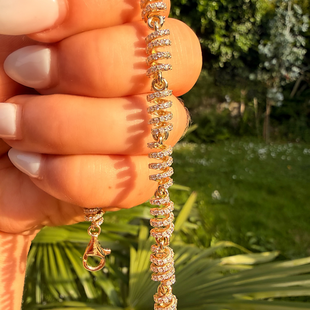 Gold necklace with crystals held by a hand against a natural background