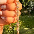 Gold necklace with crystals held by a hand against a natural background