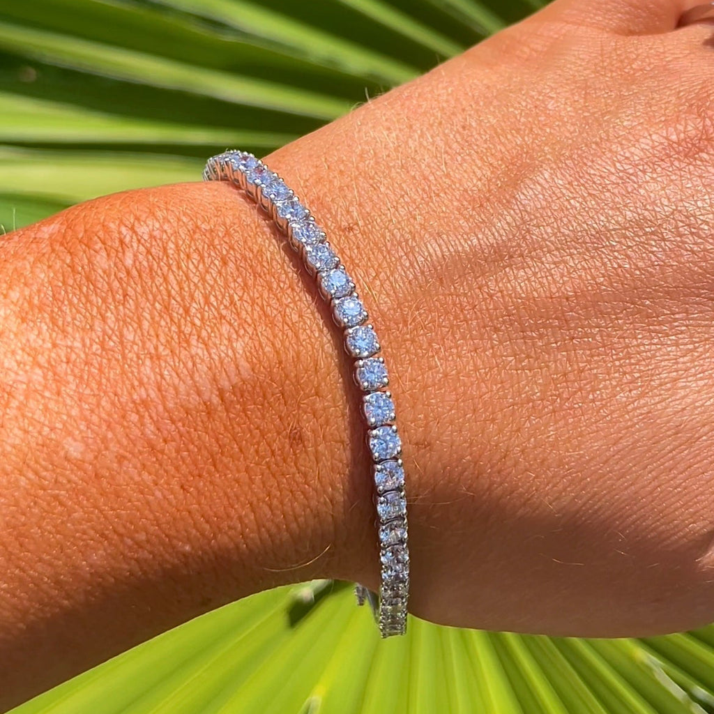 Person wearing a bracelet with a green leafy background