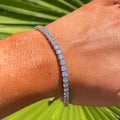 Person wearing a bracelet with a green leafy background