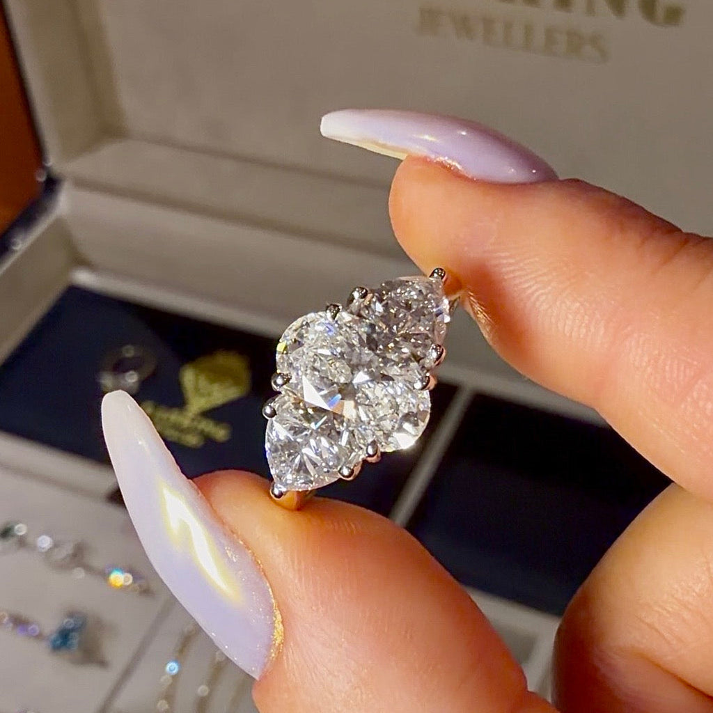 Diamond ring held between fingers with LabKing Jewellers box in the background