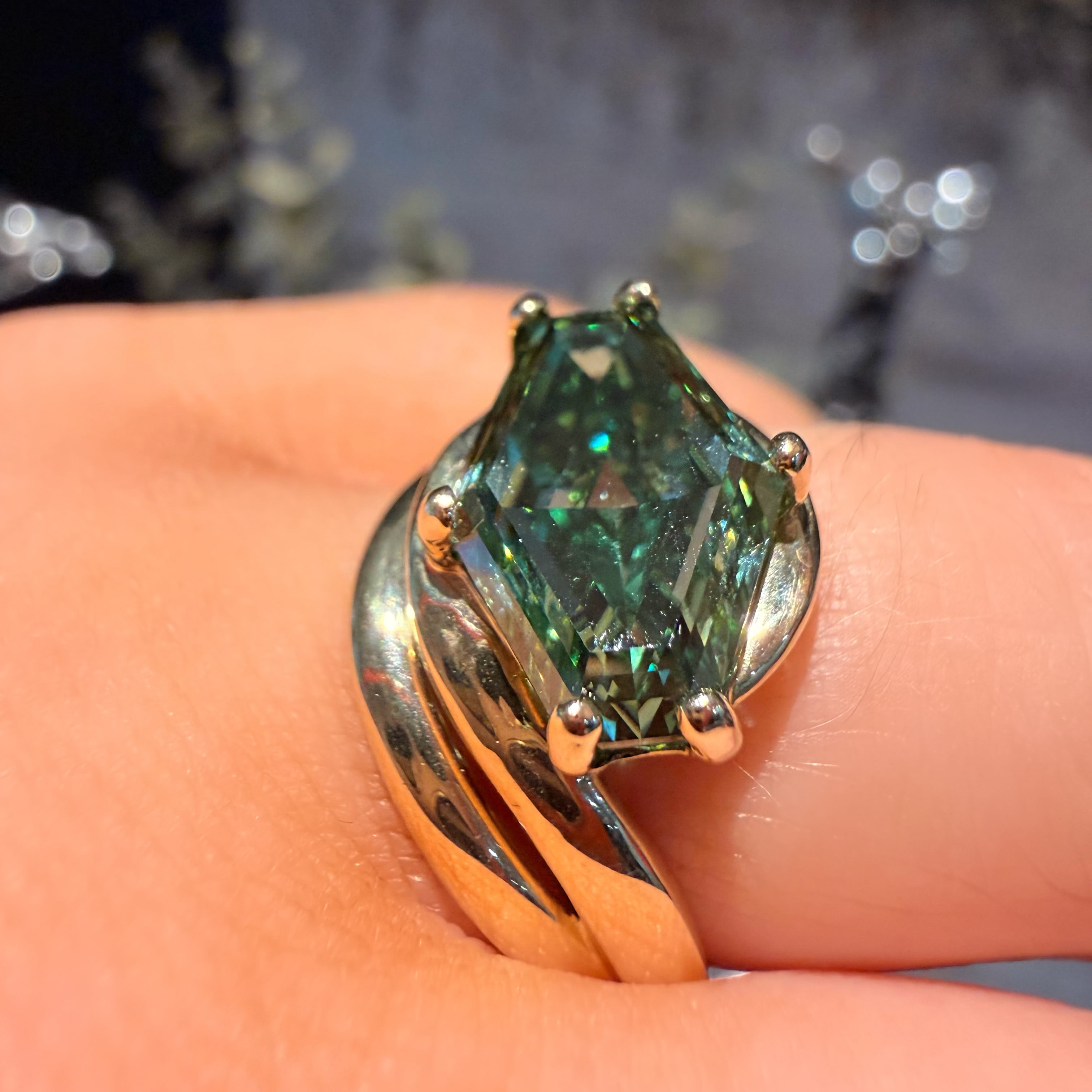 A close-up of a gold ring with a marquise-cut green gemstone worn on a finger.