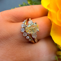 Gold ring with a large yellow gemstone on a hand with a yellow flower in the background